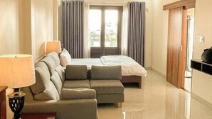 A hotel room with a bed, a sofa, a lamp, a ceiling fan, and a view of the outside. - Gio Hotel in Hue (Hue)