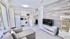 A modern apartment with a kitchen, living area, and a TV.