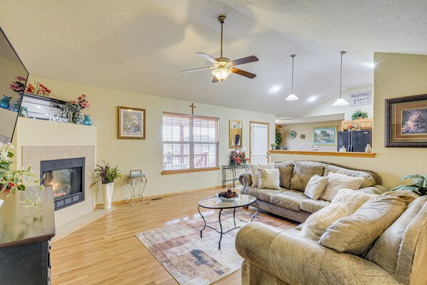 A living room with a fireplace, a ceiling fan, and a sofa.