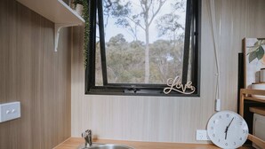 Un baño moderno con un lavabo de acero inoxidable, una ventana decorada con la palabra 'Love' y un reloj en la pared.