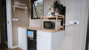 Una kitchenette compacta con microondas, un lavamanos pequeño y un lavavajillas integrado.