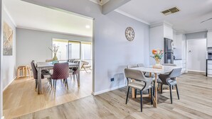 Une cuisine moderne équipée d’un réfrigérateur, d’une horloge et d’un coin repas avec une table et des chaises.