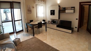 Una sala de estar moderna con comedor, un sofá, un televisor y una cocina.