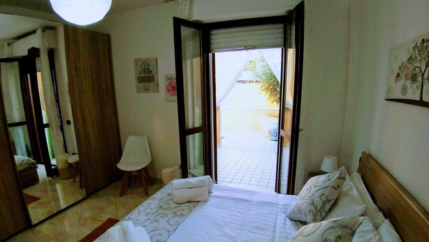 Habitación de hotel con cama, una silla, una mesita y vistas al exterior.