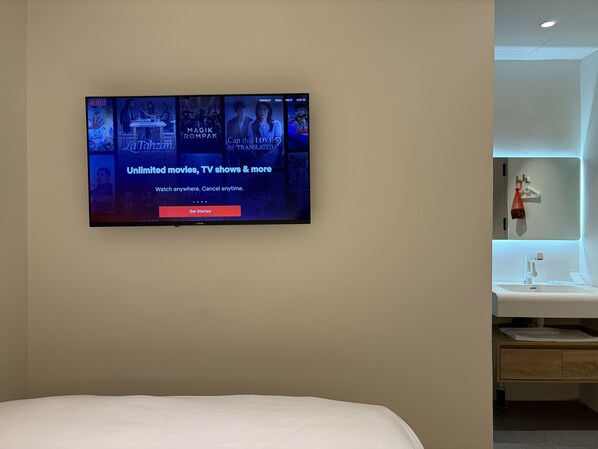 A modern hotel room with a large flat-screen TV mounted on the wall displaying a Netflix interface. - Goldlight Inn (Miri)