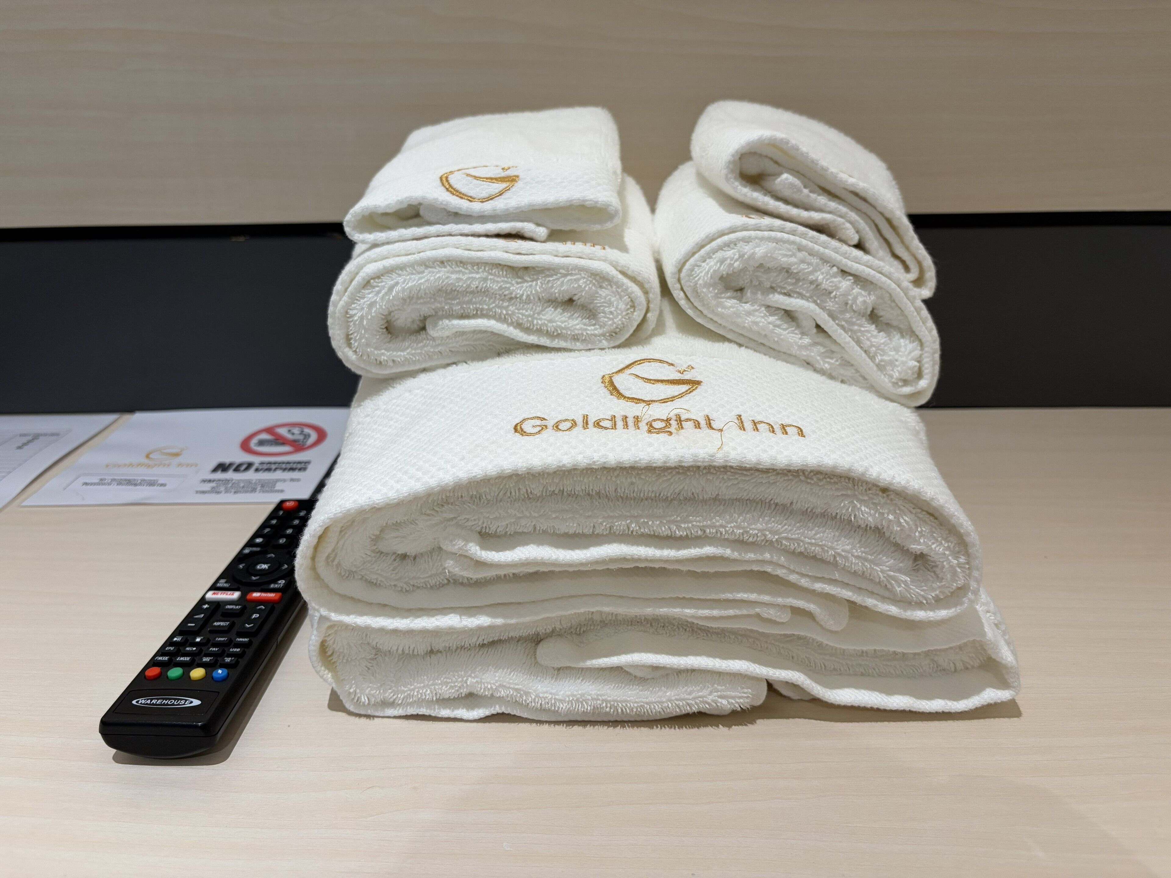 A stack of white towels with a logo and text, and a remote control.