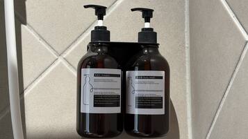 Two bottles of shampoo and body wash on a tiled wall.