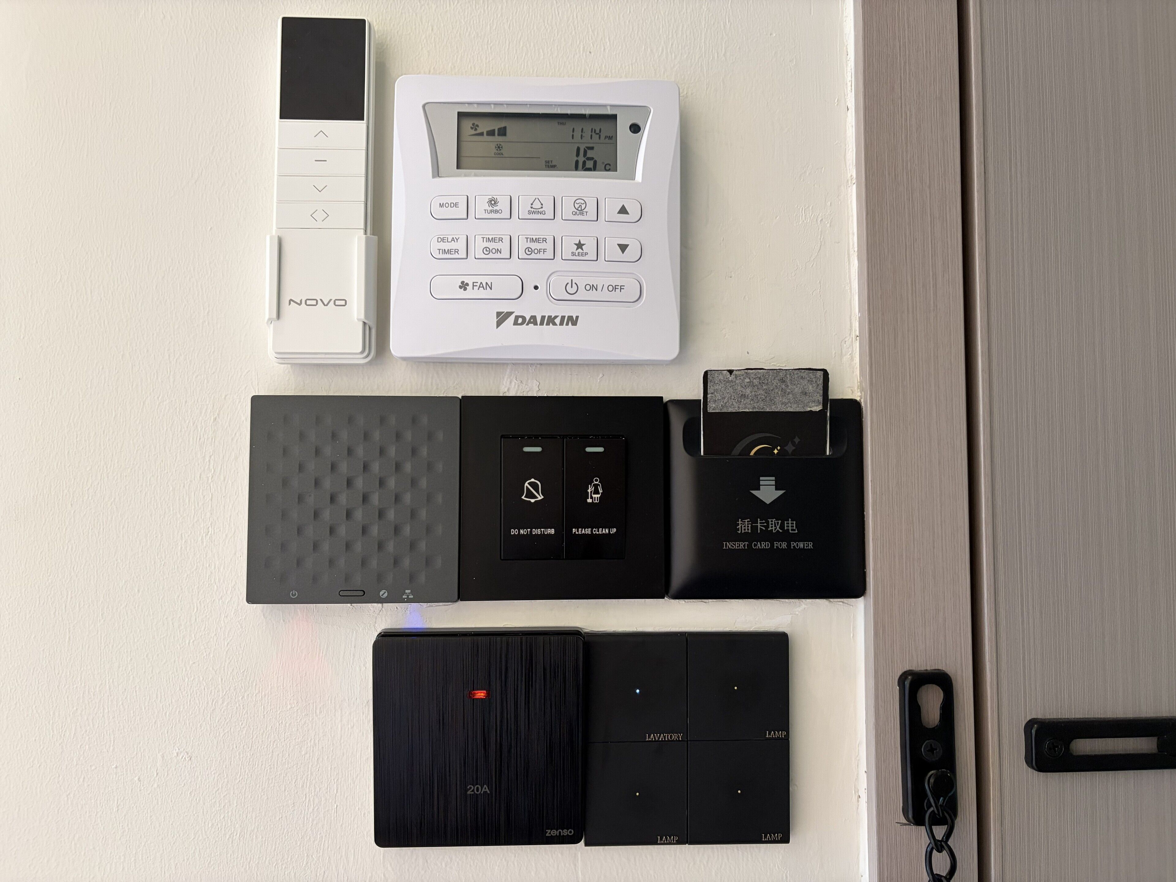 Un termostato, una regleta de enchufes, un lector de tarjetas y un cargador portátil de batería en una pared.