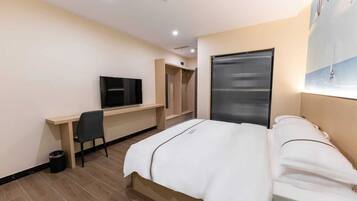 Una habitación de hotel con cama, escritorio con televisor, armario y ventana con persianas.