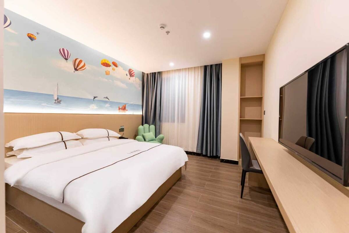 Ein Hotelzimmer mit Bett, Schreibtisch, Fernseher und einem Wandbild eines Segelboots.