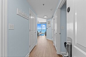 A hallway with light blue walls, white doors, and a wooden floor. - 2.5b3ba Gulf Front | Pool, Hot Tub | Beach chairs! (Panama City Beach)