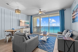 A spacious living area with a balcony, a dining table, and a sofa. - 2.5b3ba Gulf Front | Pool, Hot Tub | Beach chairs! (Panama City Beach)