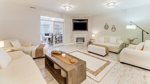A spacious living room with a fireplace, two sofas, a coffee table, and a TV mounted on the wall. - 2 Mi to Bethany Beach: Townhome w/ Pool Access! (Frankford)