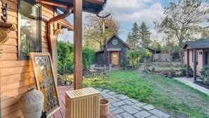 Une maison en bois avec un porche, un coin repas et un petit jardin.
