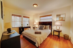 A bedroom with a large bed, two bedside tables with lamps, a dresser, and a window with blinds. - Home 1/2 Mi to Dtwn Riverside: Families Welcome! (Riverside)