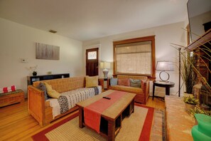 A living room with a sofa, a coffee table, a lamp, and a plant. - Home 1/2 Mi to Dtwn Riverside: Families Welcome! (Riverside)
