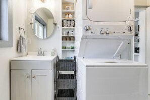 Une salle de bain moderne avec un lavabo, un miroir et un lave-linge blanc.