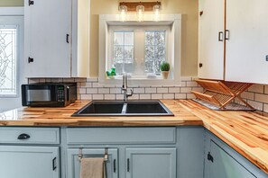 Une cuisine dotée d’un plan de travail en bois, d’un évier encastré et d’armoires.