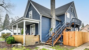 Une maison à deux étages dotée d’un porche, d’une terrasse en bois et d’un escalier menant à l’étage supérieur.