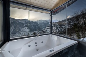 Ein modernes Badezimmer mit einer großen Badewanne, einem Fenster mit Bergblick und einer Holzboden.