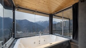 A modern bathroom with a large bathtub, a wooden ceiling, and a view of mountains. - Echor Himalayan Sky Cabins Sethan Manali (Manali)