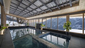 A modern indoor swimming pool with a wooden ceiling and large windows offering a mountain view. - Echor Himalayan Sky Cabins Sethan Manali (Manali)
