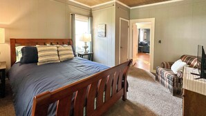 A bedroom with a wooden bed, a ceiling fan, a nightstand, a lamp, a plaid sofa, and a television. - 'The Vineyard House' - 2 Mi to Dtwn Mount Airy! (Mt Airy)