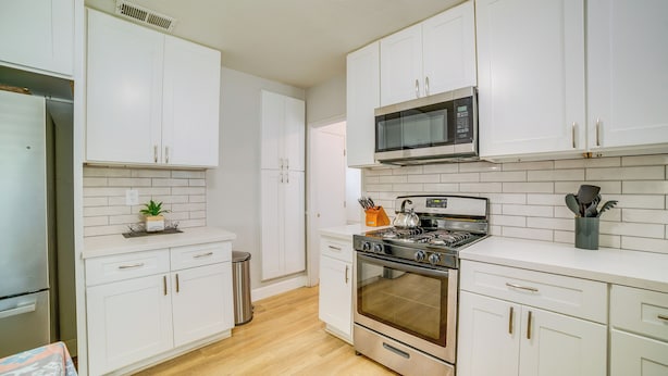A modern kitchen with white cabinets, a stainless steel refrigerator, a microwave, and an oven. - Family-Friendly Home 2 Mi to Dtwn Riverside (Riverside)