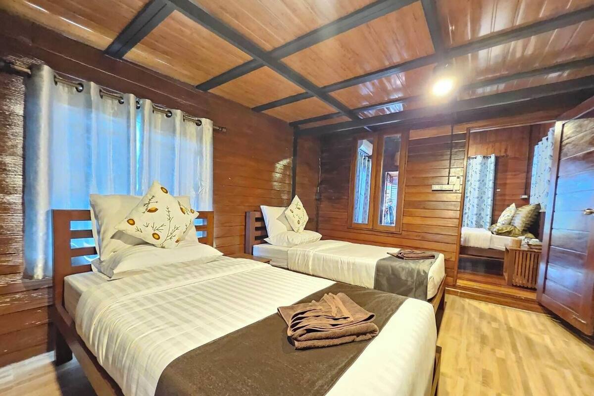 Ein holzgetäfeltes Zimmer im Blockhausstil mit zwei Betten, einem kleinen Tisch und einem Kleiderschrank.