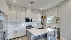 A modern kitchen with white cabinets, a stainless steel refrigerator, a microwave, and a sink. - Easy Beach Access! Port A Oasis w/ Private Pool (Port Aransas)