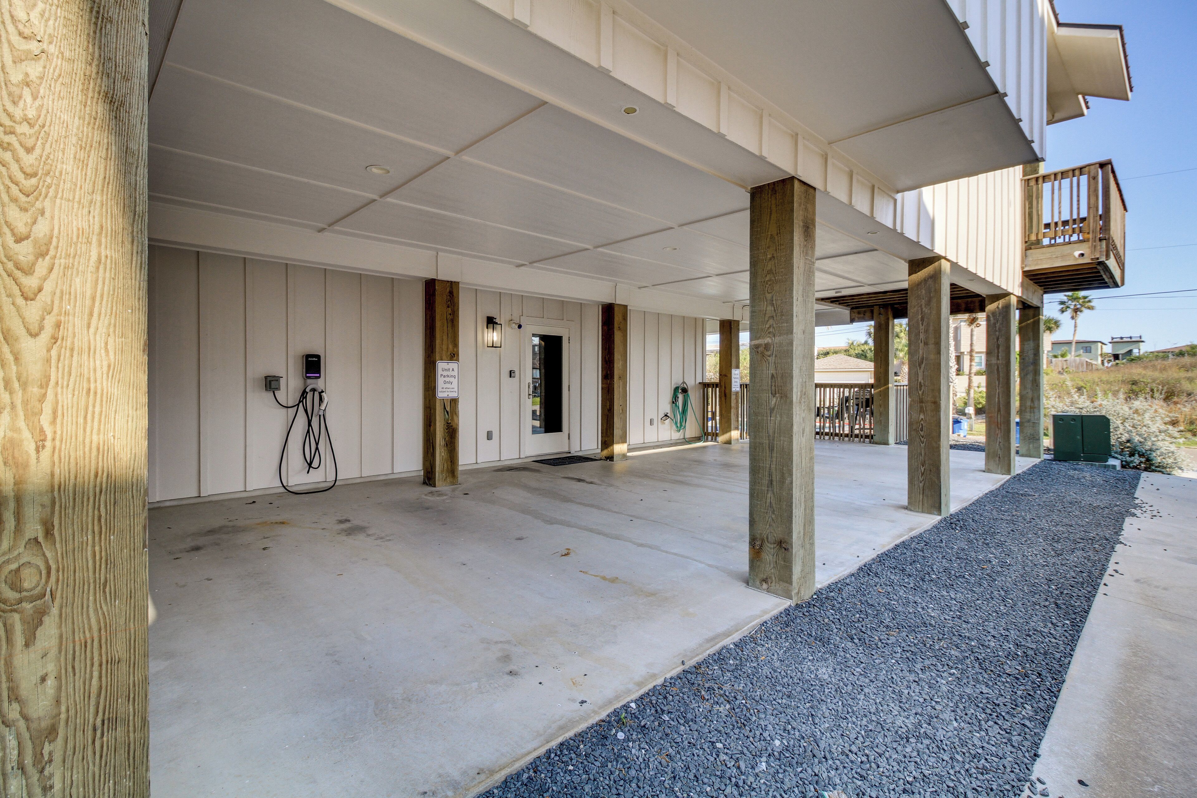 Un espace extérieur abrité, doté d’un sol en béton, de piliers en bois et d’un petit balcon.