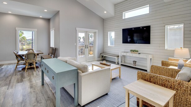 A spacious living room with a dining area, a large TV mounted on the wall, and a cozy seating arrangement. - Easy Beach Access! Port A Oasis w/ Private Pool (Port Aransas)