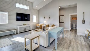 A spacious living room with a large flat-screen TV, a light blue sofa, and a wooden coffee table. - Easy Beach Access! Port A Oasis w/ Private Pool (Port Aransas)