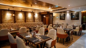 A restaurant with a stone wall, wooden ceiling, and multiple dining tables with chairs. - The Rosendale Srinagar (Srinagar)