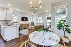 Une cuisine moderne avec des meubles blancs, un coin repas doté d’une table ronde pour quatre personnes et une grande fenêtre donnant sur l’extérieur.