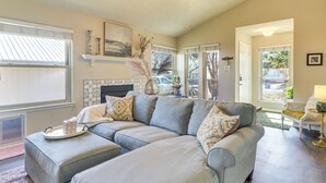A living room with a grey sectional sofa, a ceiling fan, and a fireplace. - ATX Urban Oasis: Cowboy Pool + Fenced Yard (Austin)