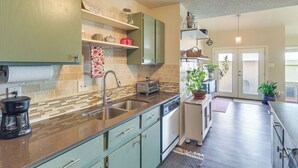 A modern kitchen with a dishwasher, a coffee maker, and a toaster. There are cabinets, a sink, and a window. - ATX Urban Oasis: Cowboy Pool + Fenced Yard (Austin)