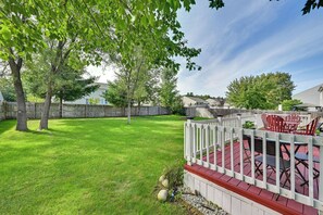 A backyard with a wooden deck, a white picket fence, and a patio area with outdoor furniture. - Spacious Family Getaway w/ Yard in Kalamazoo! (Kalamazoo)
