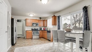 A kitchen with wooden cabinets, a white countertop, and a dining area with two chairs. - Spacious Family Getaway w/ Yard in Kalamazoo! (Kalamazoo)