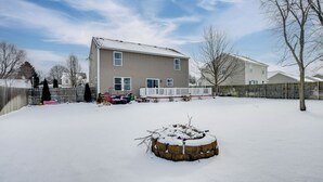 A residential house with a snow-covered yard and a wooden deck. - Spacious Family Getaway w/ Yard in Kalamazoo! (Kalamazoo)