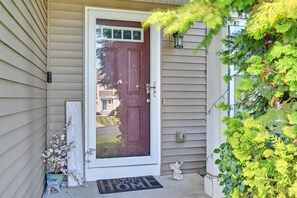 A house entrance with a red door, a welcome mat, a mailbox, and a small decorative angel. - Spacious Family Getaway w/ Yard in Kalamazoo! (Kalamazoo)