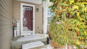 A house with a front door, steps, and a snow-covered porch. - Spacious Family Getaway w/ Yard in Kalamazoo! (Kalamazoo)