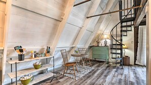 Habitación estilo loft con zona de comedor que incluye sillas de madera, una mesa, un mueble verde y una escalera de caracol.