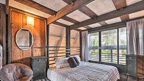 Un dormitorio con una cama grande, una silla, un armario, un espejo y una ventana con vistas al exterior.