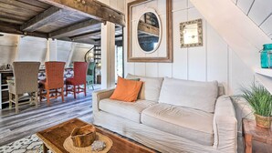 Una sala de estar acogedora con un sofá, sillas, una mesa de centro de madera y un espejo grande en la pared.