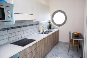 A modern kitchen with a built-in microwave, a sink, and a round window above the counter. - Apartments in Villa Fortunata (Terracina)