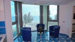 A room with large windows, a blue tiled floor, and two blue chairs. - Apartments in Villa Fortunata (Terracina)