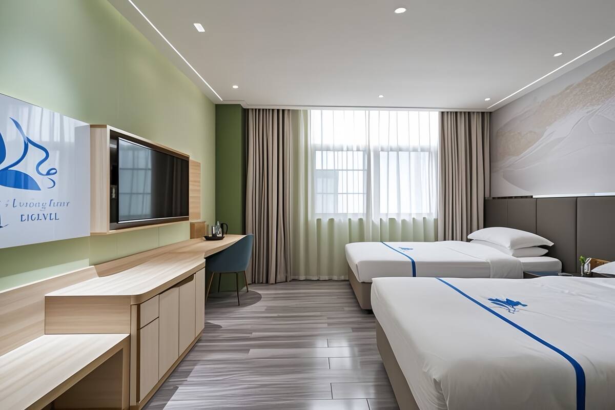 Ein Hotelzimmer mit Schreibtisch, zwei Betten, Fernseher und einem großen Fenster mit Vorhängen.