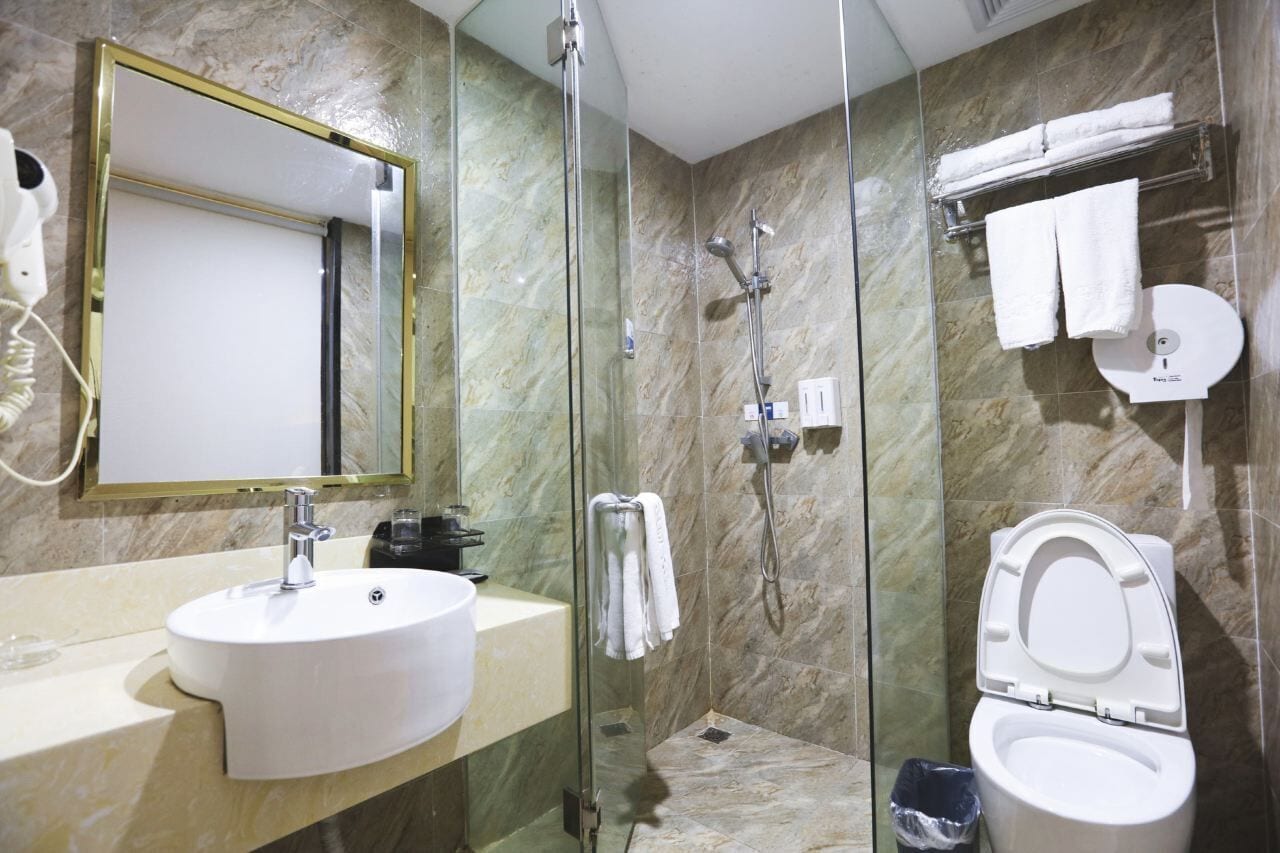 Un baño con lavabo, espejo, ducha e inodoro.