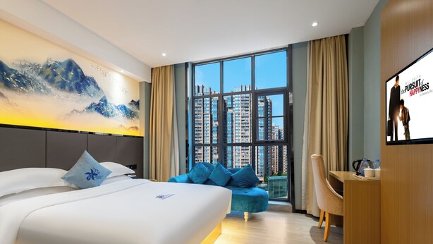 A modern hotel room with a large bed, a desk, a sofa, and a large window offering a city view. - AeroLink Hotel Shenzhen Bao'an Airport  (Shenzhen)